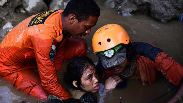 Para relawan membantu Nurul -15 tahun- yang tertimbun dalam reruntuhan selama dua hari